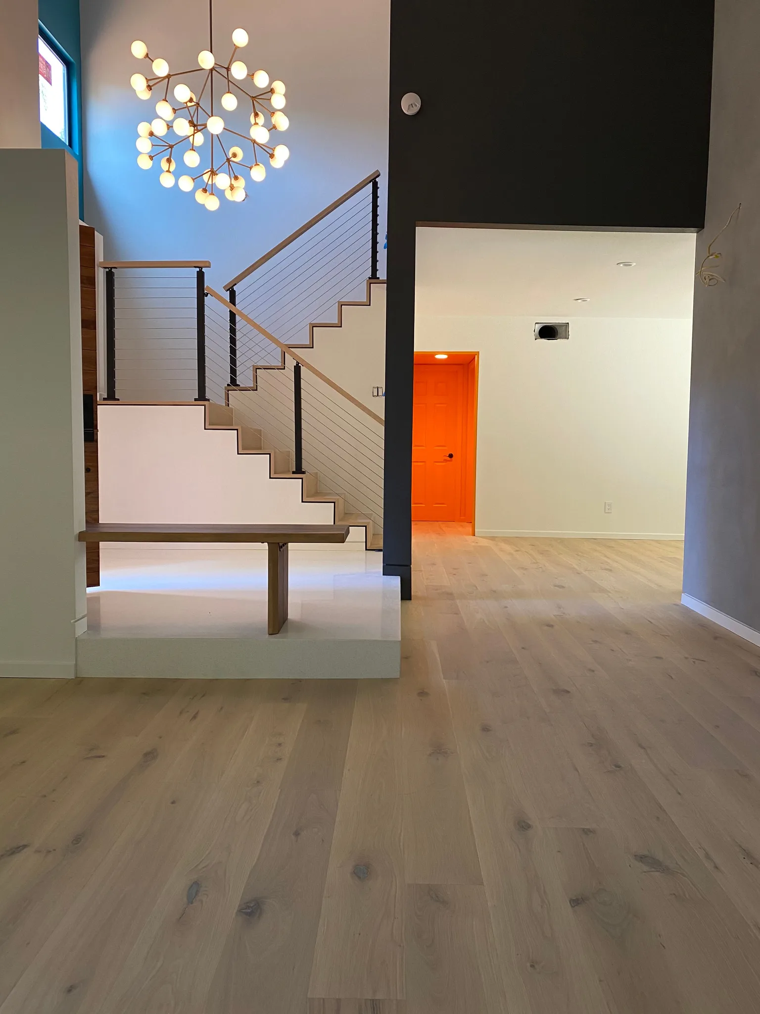 White oak planks at the foot of the stair under the branching chandelier in Agoura Hills