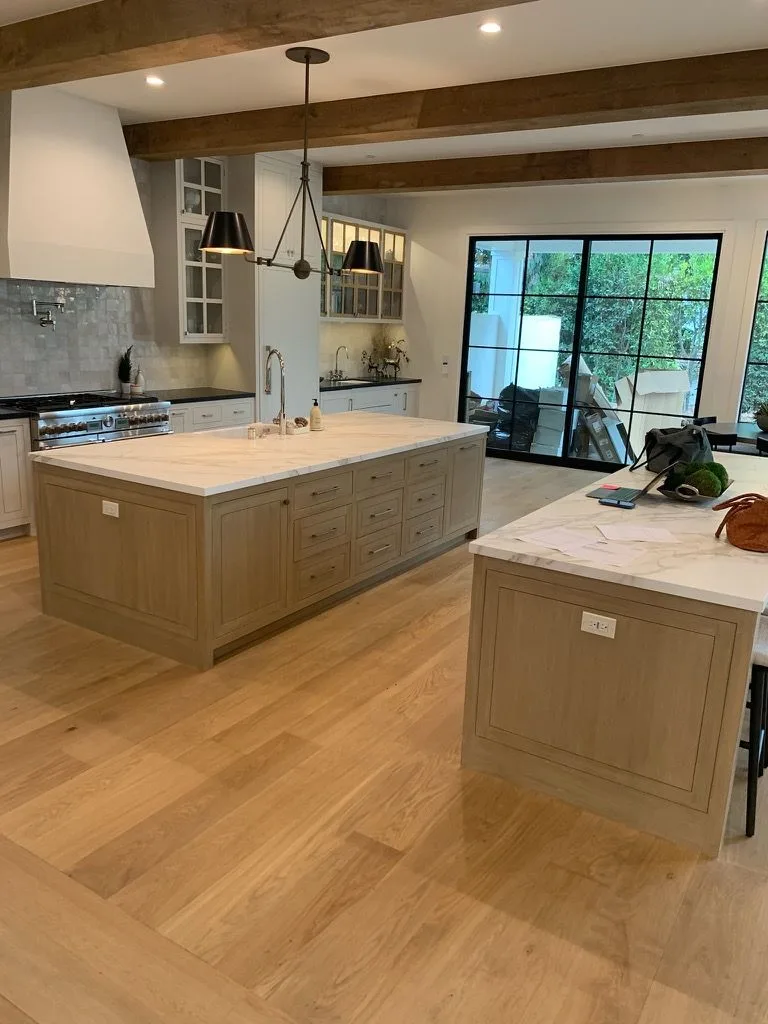 Natural white oak planks through a kitchen with oak islands and marble tops in Manhattan Beach