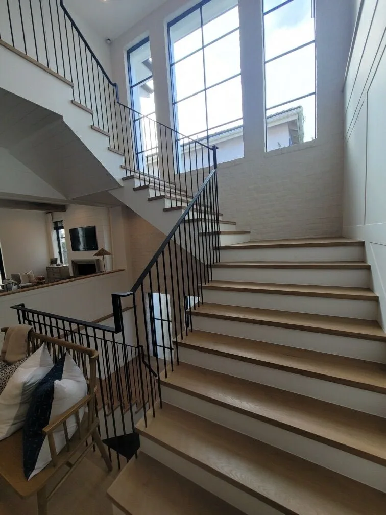 White oak stair with iron balusters at the double-height window in Manhattan Beach