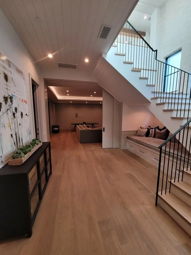 White oak treads landing at a lower hallway, planks running to the lounge in Manhattan Beach