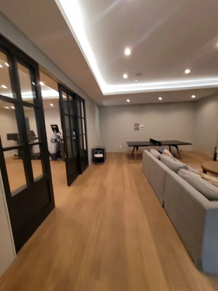 Wide-plank white oak in a lower-level lounge with steel-framed glass doors in Manhattan Beach