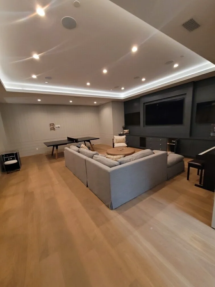 Wide-plank white oak across a media room with a coved ceiling in Manhattan Beach