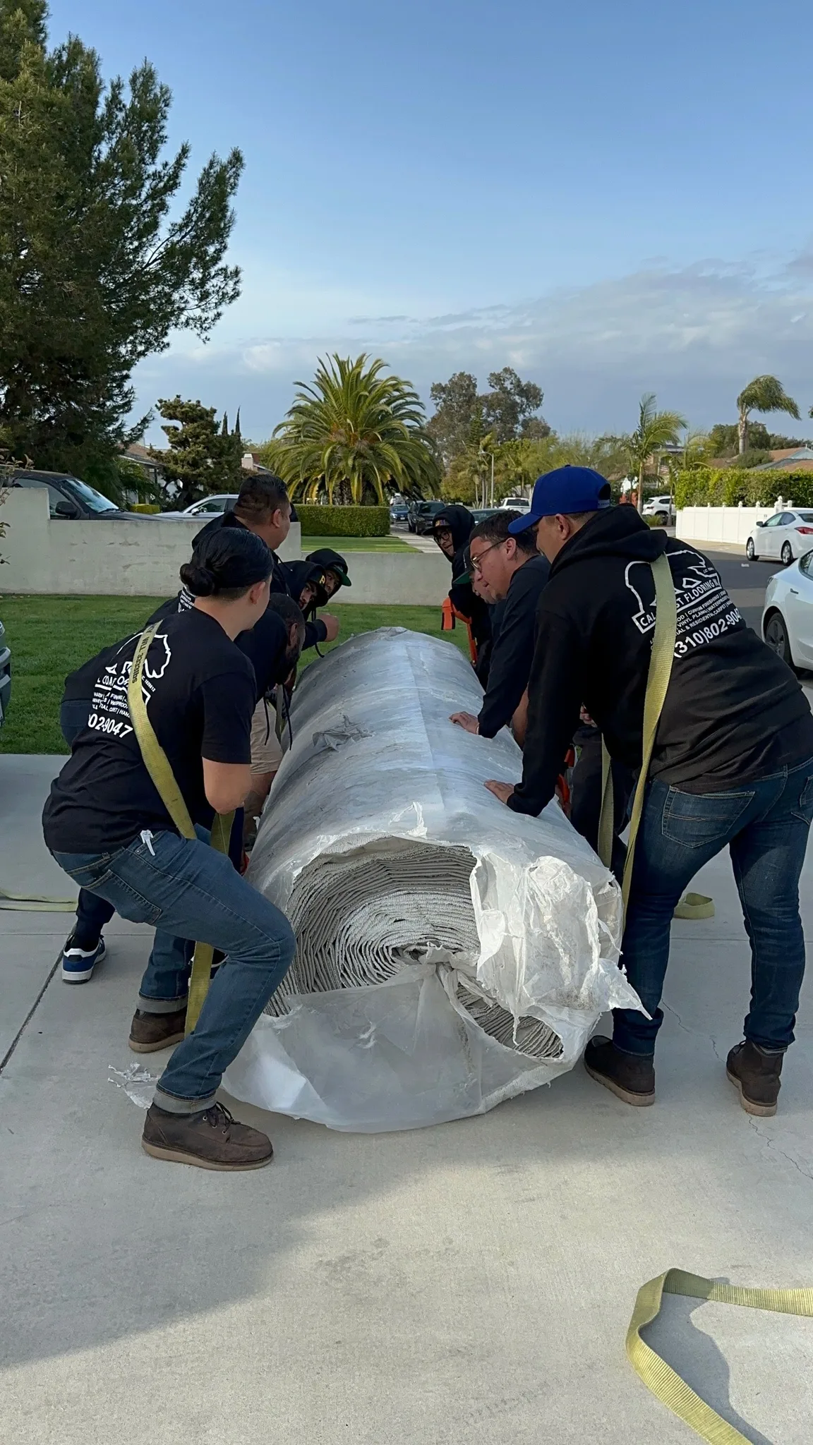 Crew carrying a carpet roll in on straps