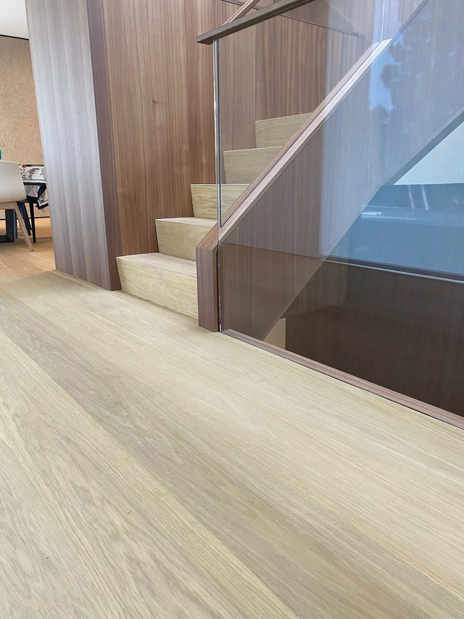 European oak at the foot of the stair, walnut paneling and glass rail in Santa Monica
