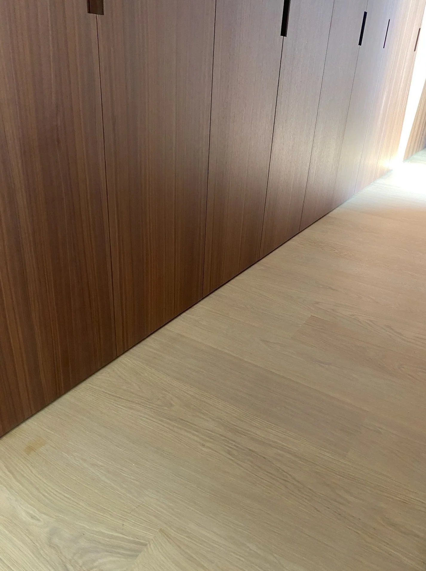 Wide oak planks meeting walnut-paneled closets in the hallway in Santa Monica