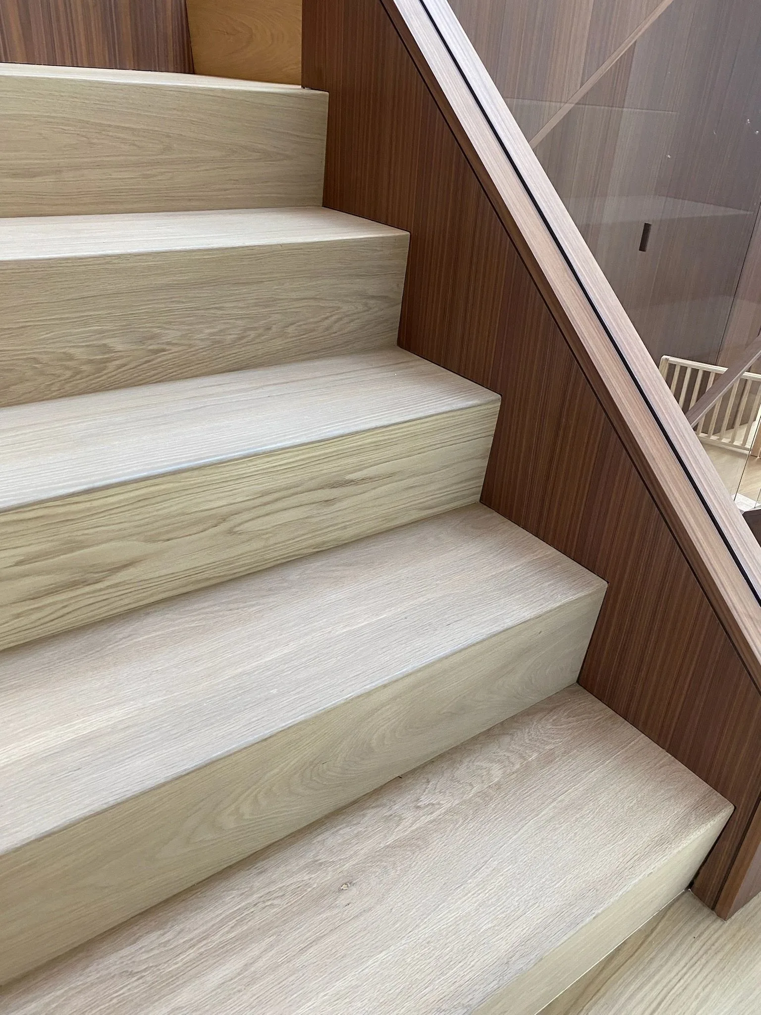 European oak treads and risers between walnut paneling and glass in Santa Monica