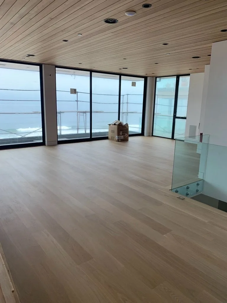 Wide-plank white oak across an ocean-facing room under a cedar ceiling in Redondo Beach