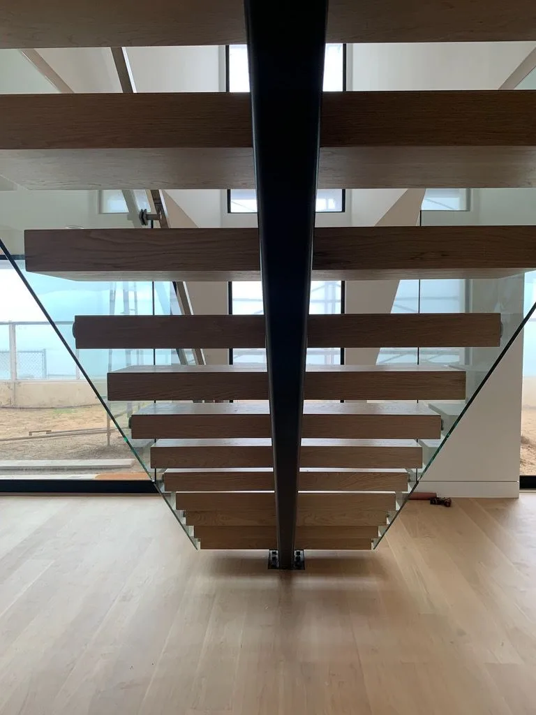 Underside of the floating white oak stair, treads cantilevered off the center stringer in Redondo Beach