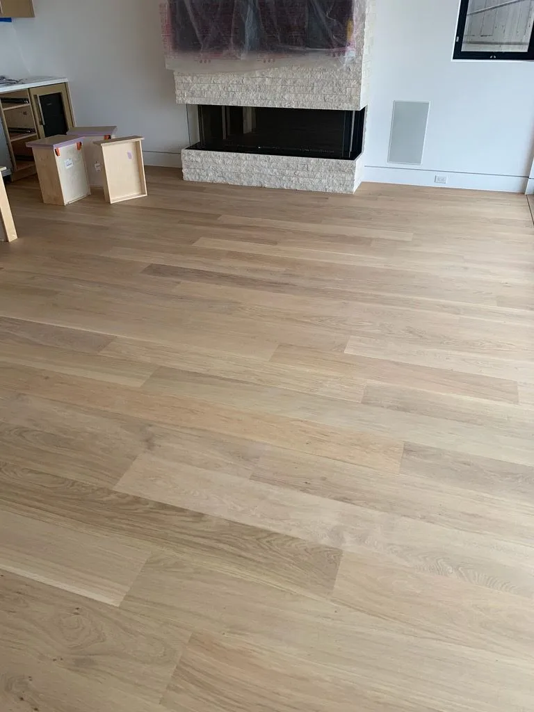 Natural-finish white oak planks running past a stone fireplace in Redondo Beach