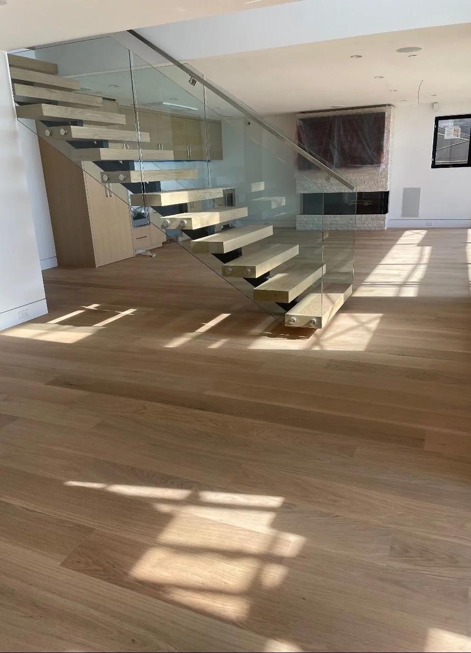 Floating oak treads behind glass, afternoon light across the planks in Redondo Beach