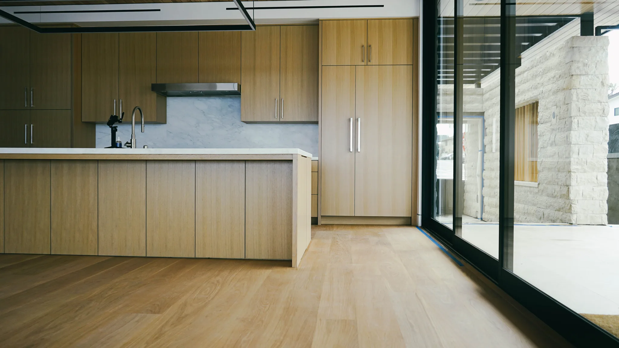 Kitchen with oak cabinetry on wide-plank white oak, sliders open to the patio in Redondo Beach