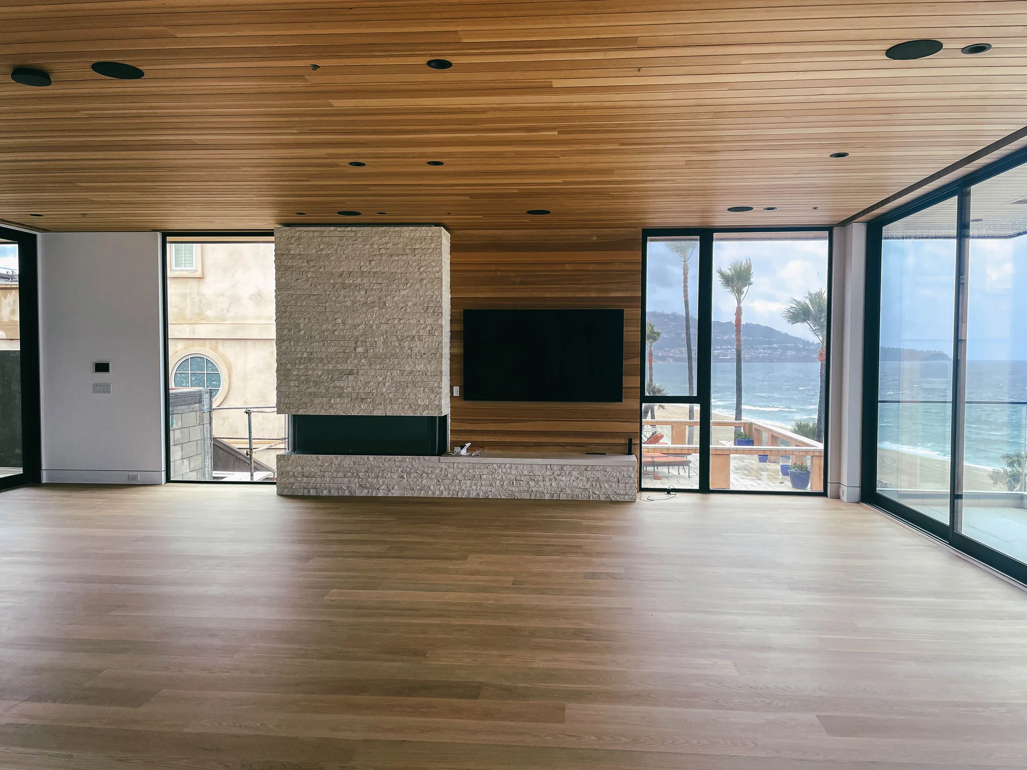 Wide-plank white oak through an open living room, fireplace and ocean view in Redondo Beach