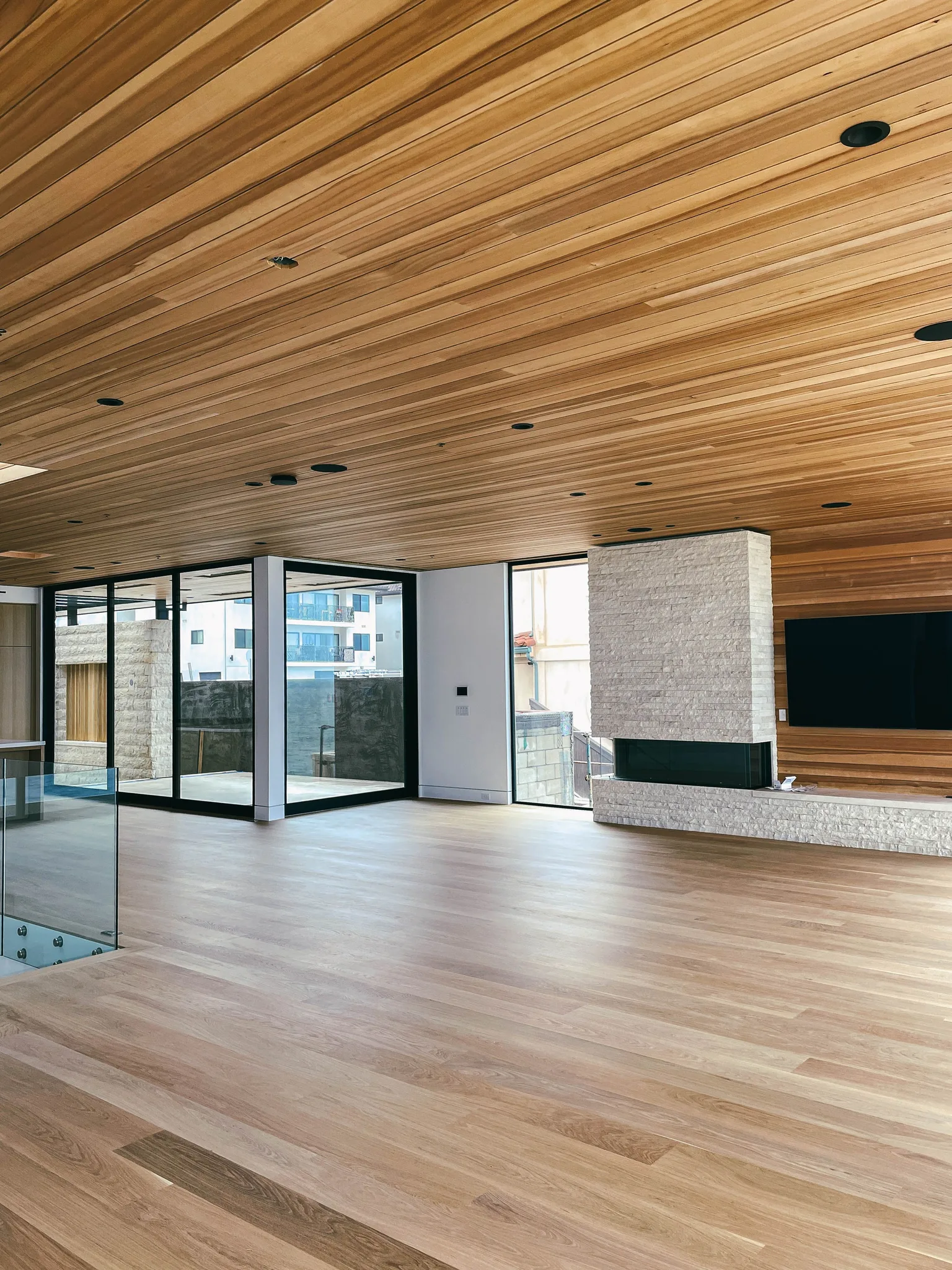 Oak planks under a cedar-plank ceiling, glass stair rail at the edge of the room in Redondo Beach