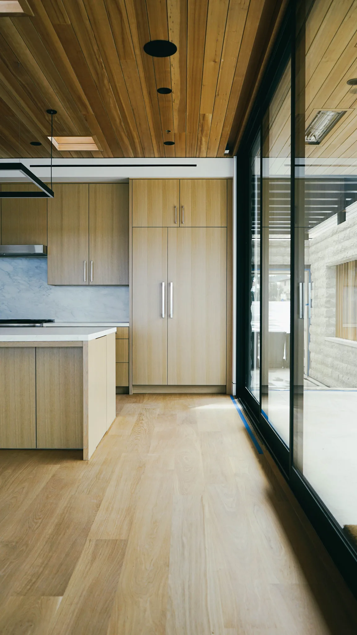 Natural-finish white oak running from the kitchen to the sliding glass wall in Redondo Beach
