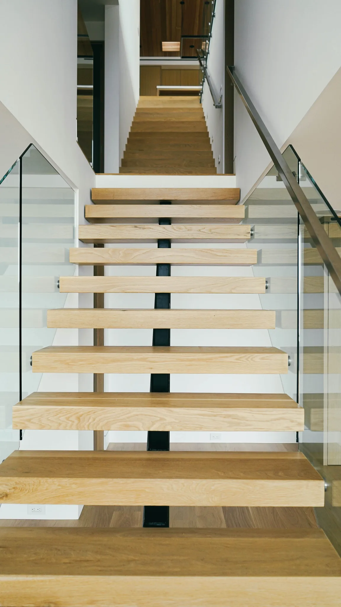 Floating white oak treads from below, glass rails on both sides in Redondo Beach
