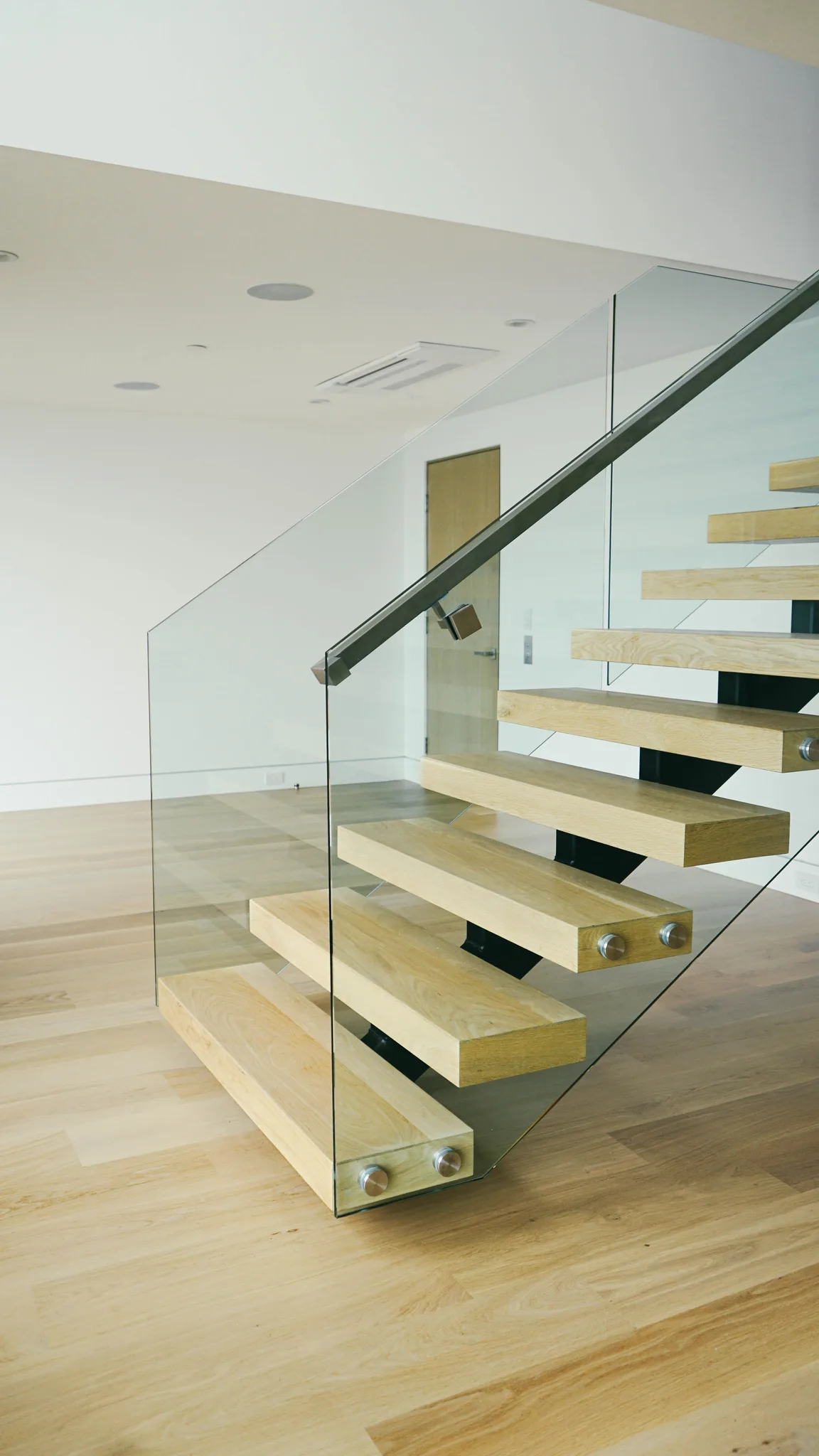 Floating oak treads on the center stringer, glass rail with a steel handrail in Redondo Beach
