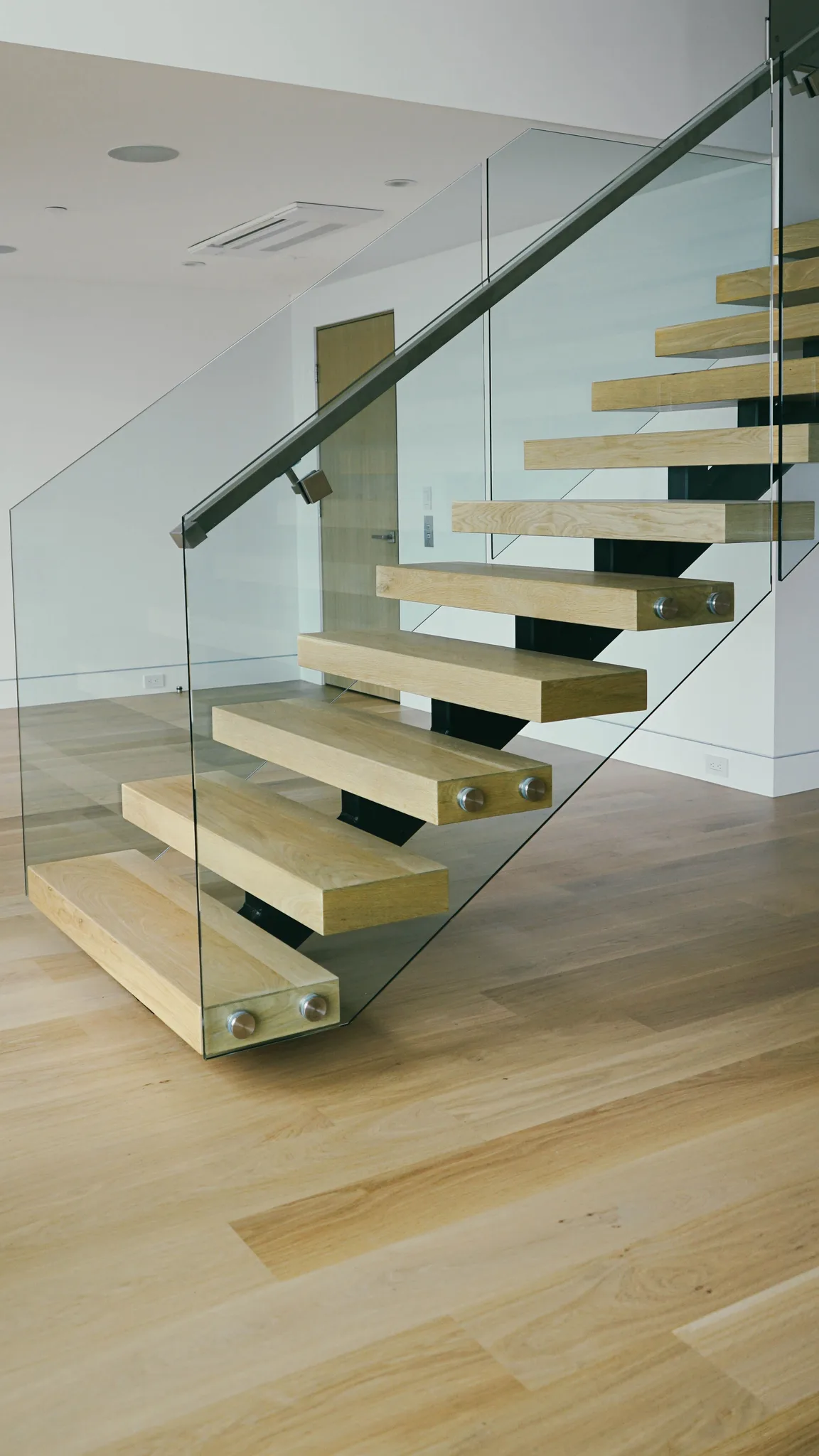 Floating oak treads behind a glass rail, wide-plank oak at the landing in Redondo Beach