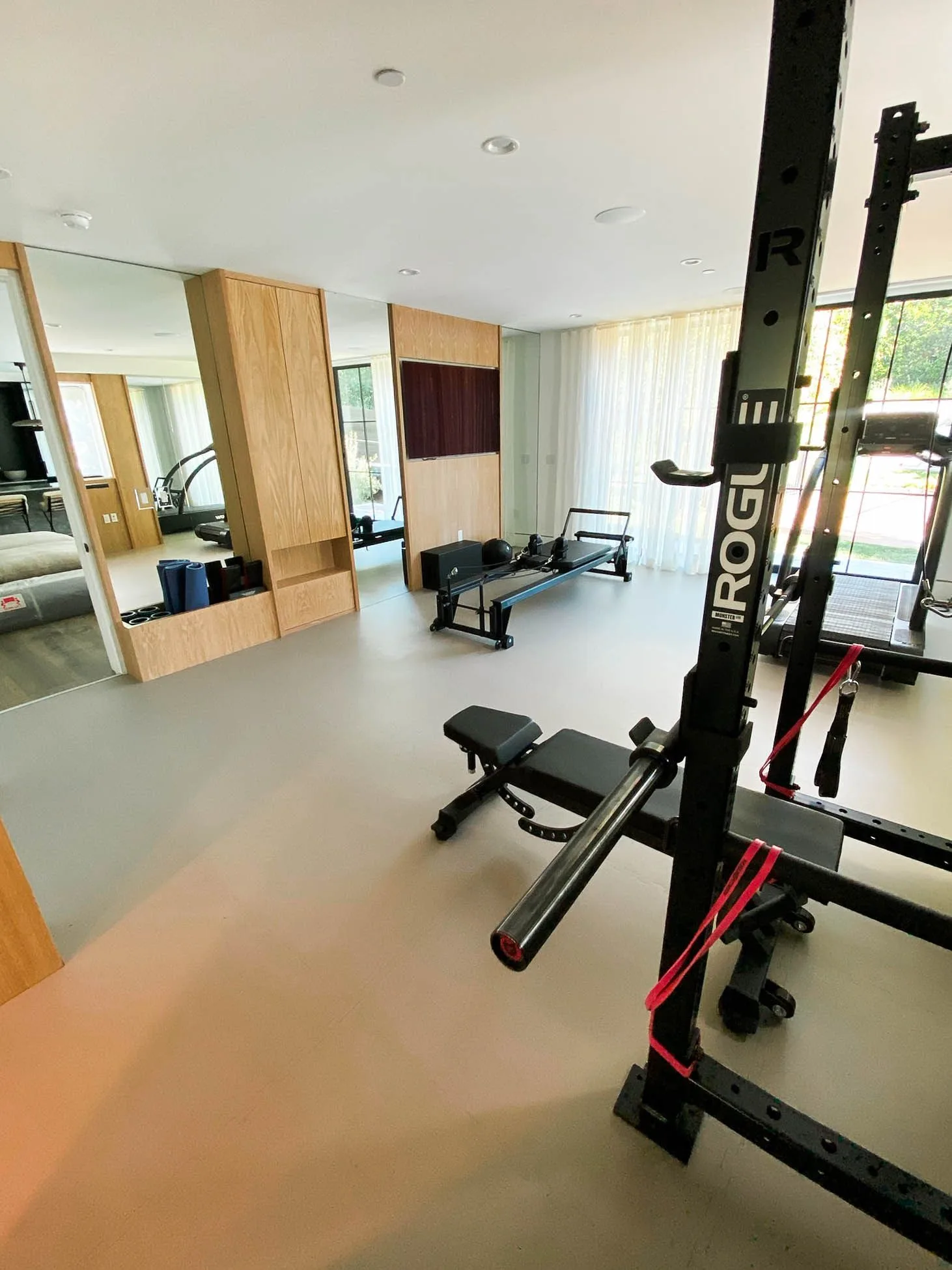 Grey interlocking rubber gym floor around a squat rack and bench, oak cabinetry beyond
