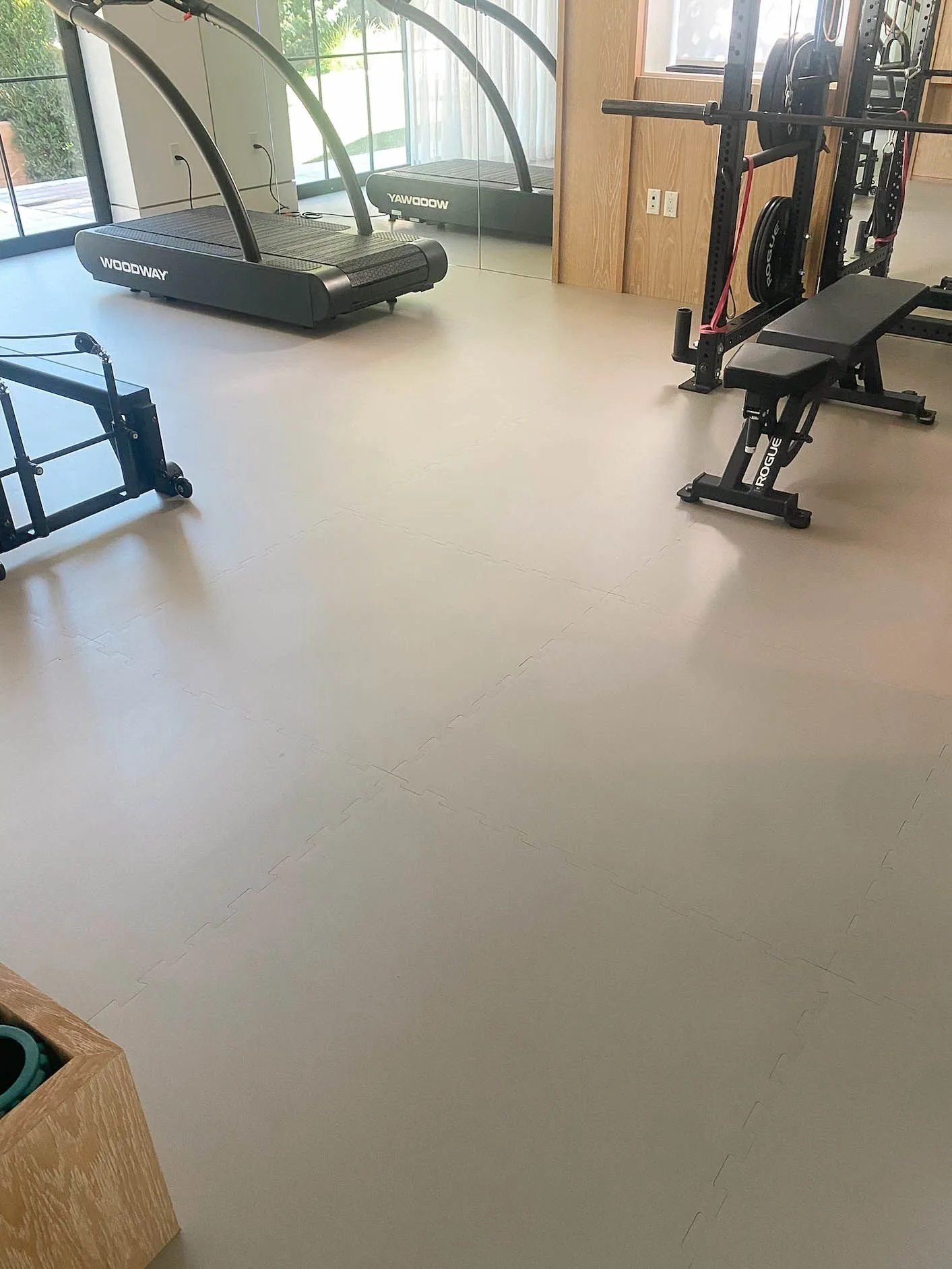 Grey interlocking rubber tiles across a home gym, treadmill and bench at the far wall