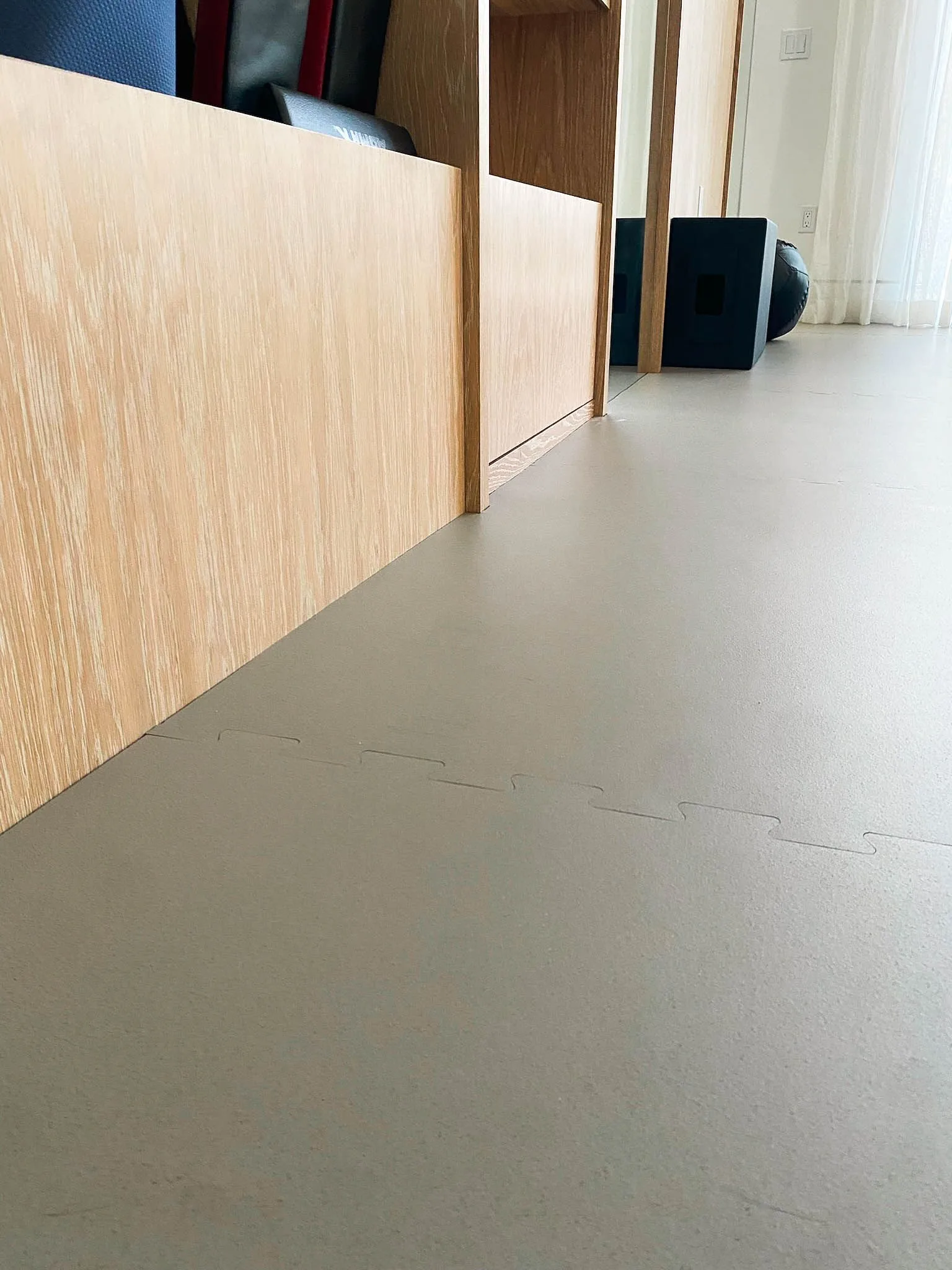 Interlocking rubber tiles fitted against oak built-ins in a home gym