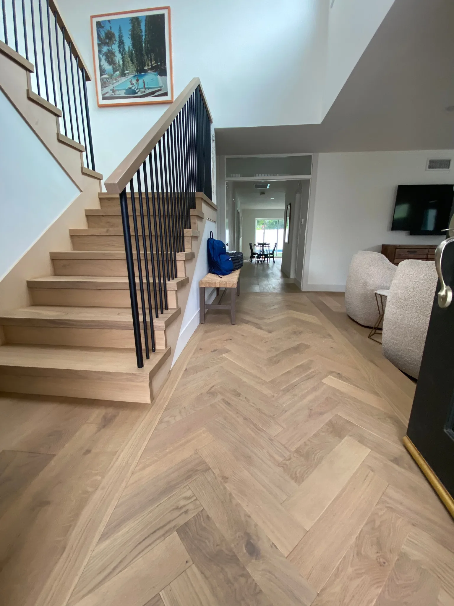 Oak handrail on black steel balusters beside a herringbone oak floor