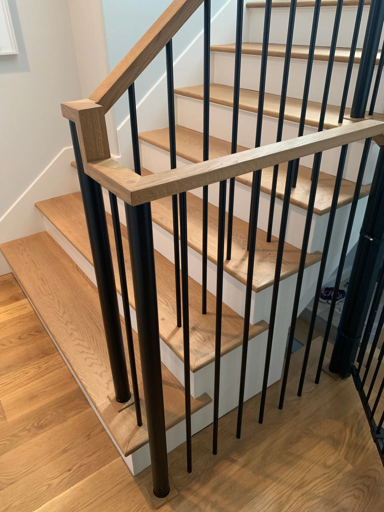 Square-profile oak handrail with a mitred turn on black round balusters
