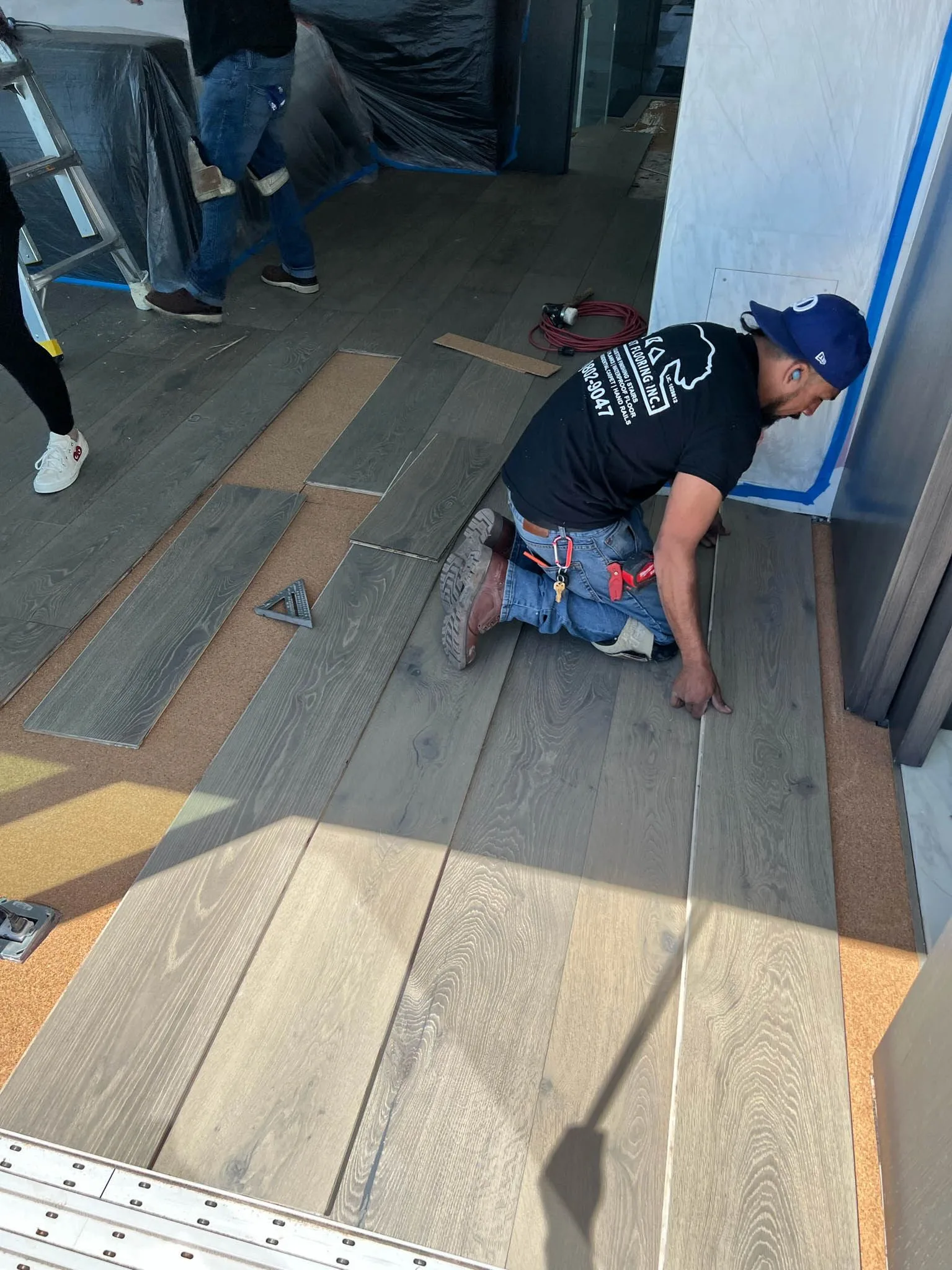Laying grey wide-plank flooring over cork