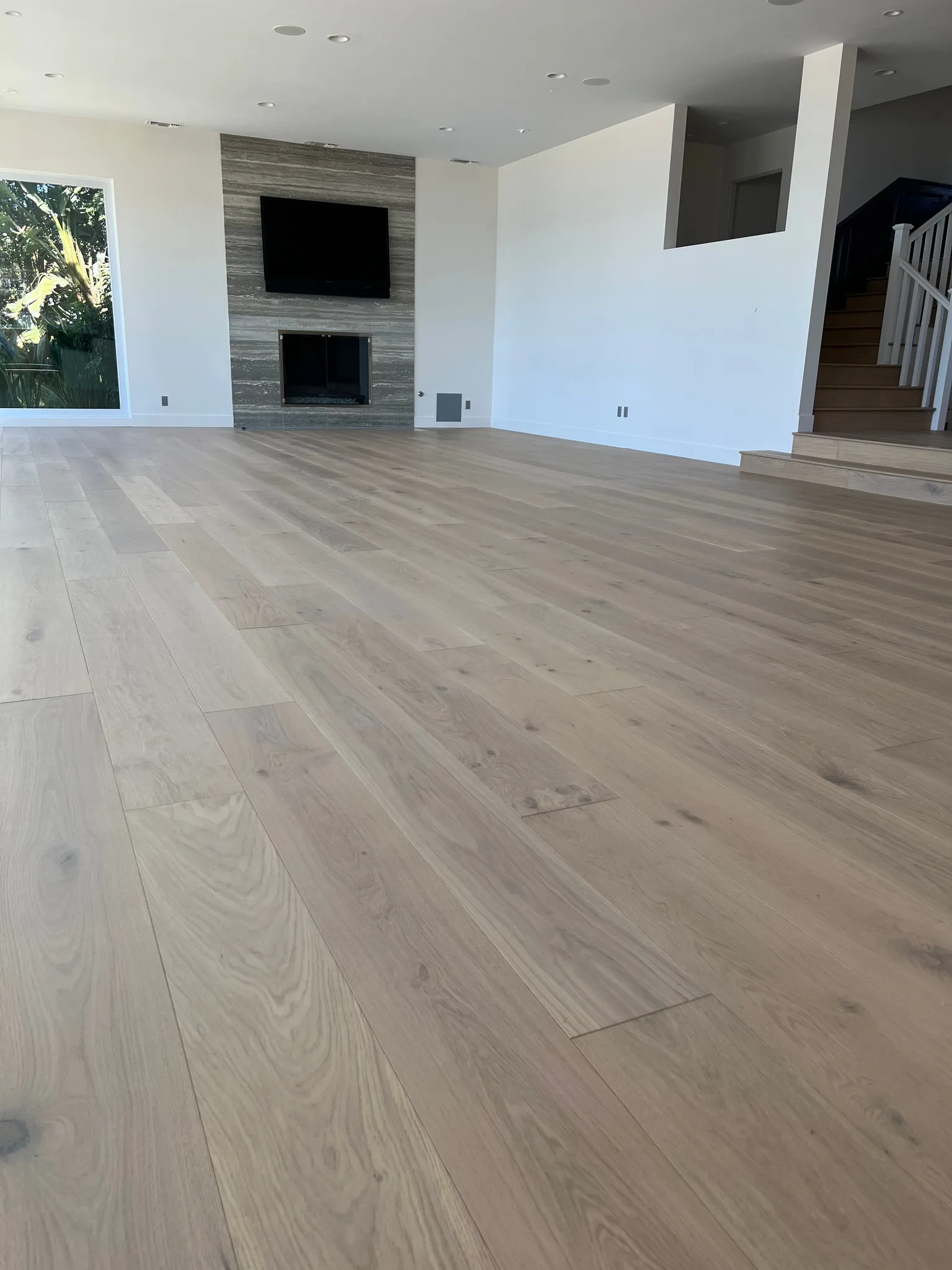Light wide-plank oak with a matte finish in front of a stone fireplace