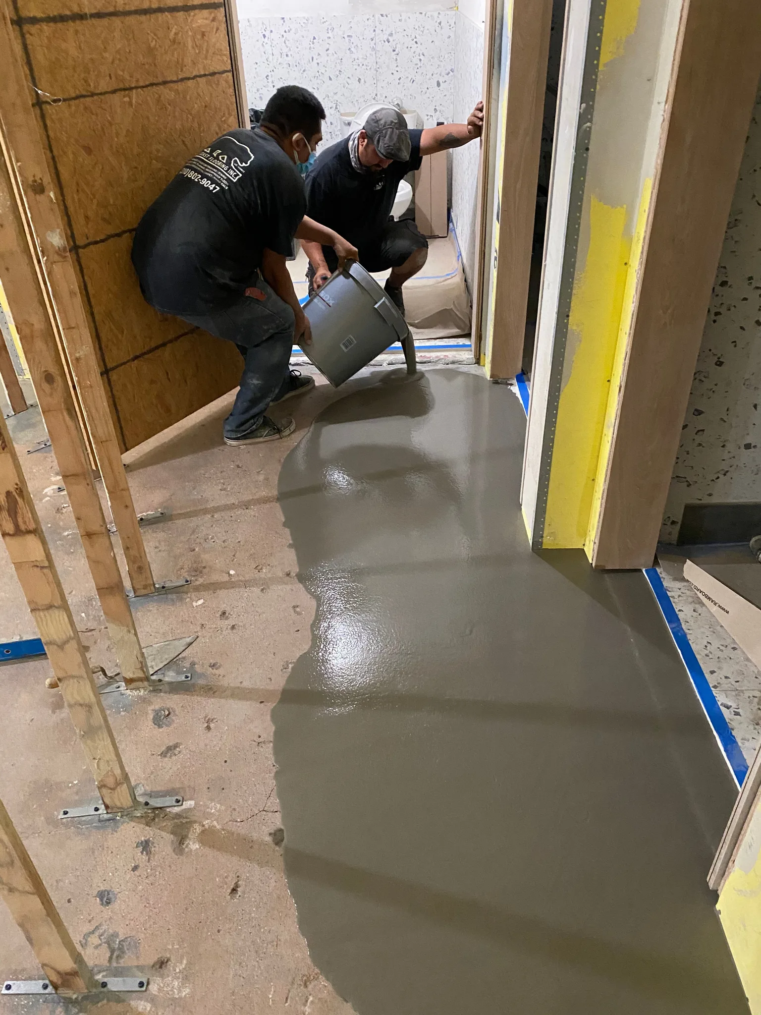 Crew pouring self-leveling compound in a hallway