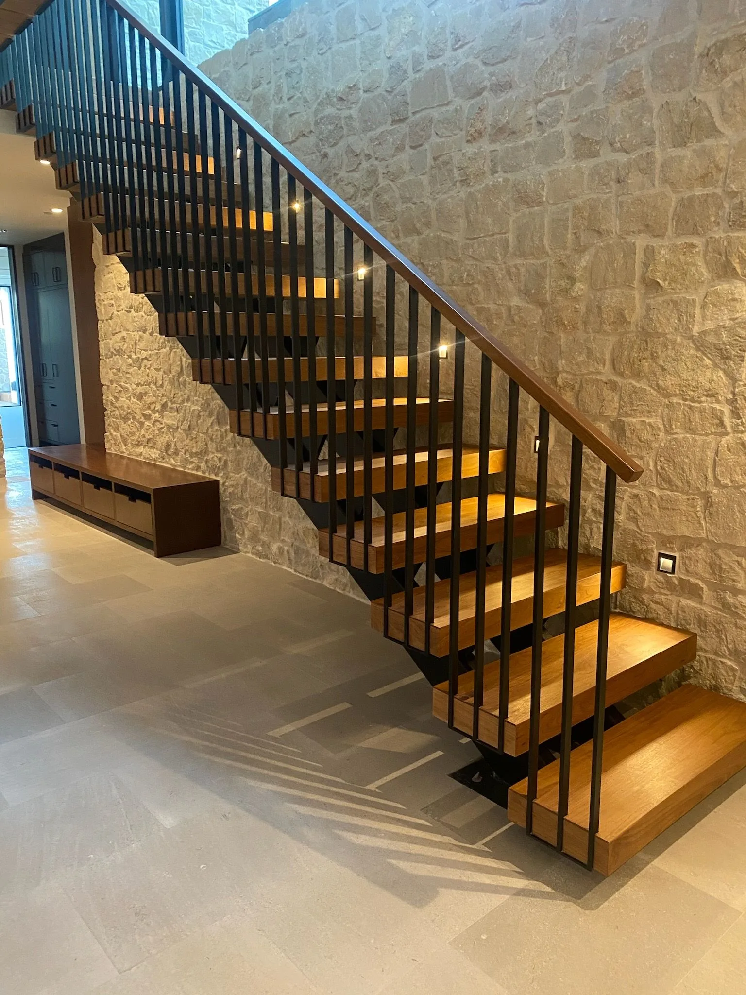 Floating walnut treads on a steel frame against a stone wall in Hermosa Beach