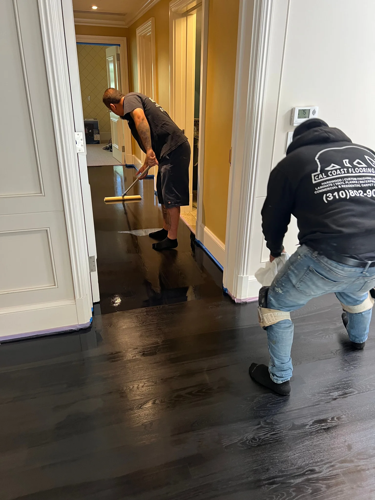 Crew coating a black-stained hallway floor