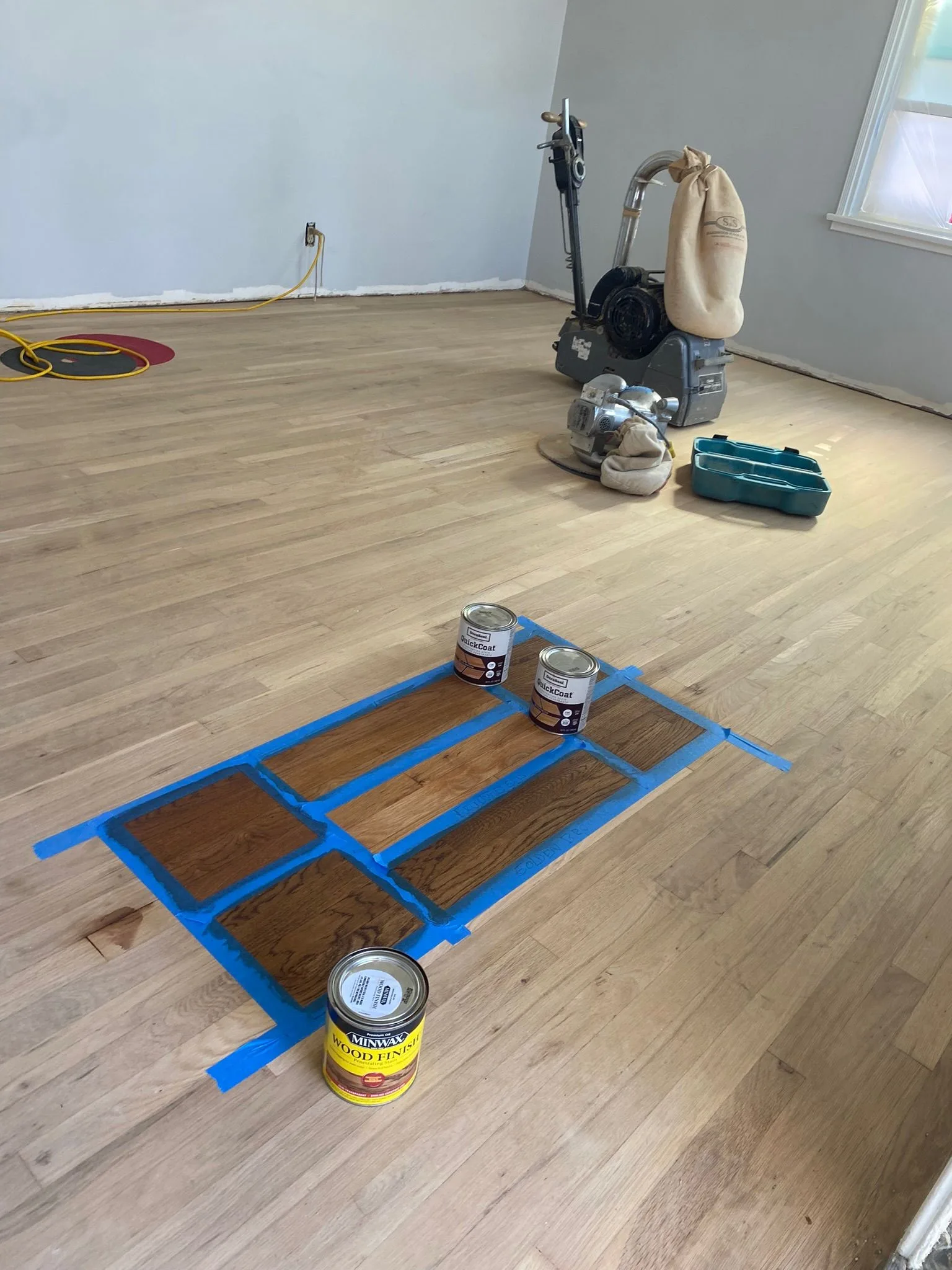 Stain samples taped out on a sanded strip floor