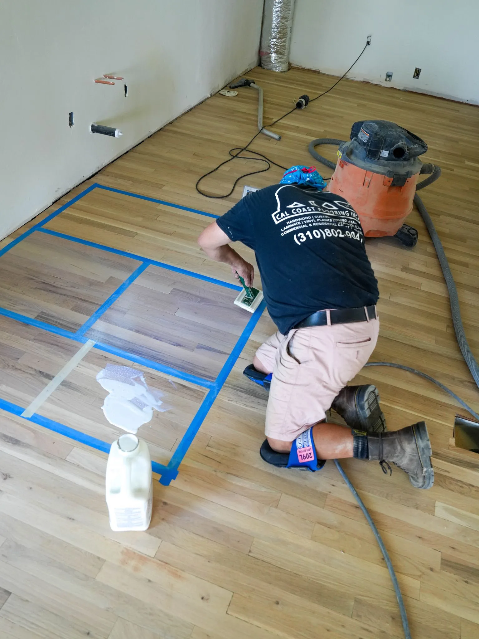 Brushing stain samples into a taped grid on sanded oak