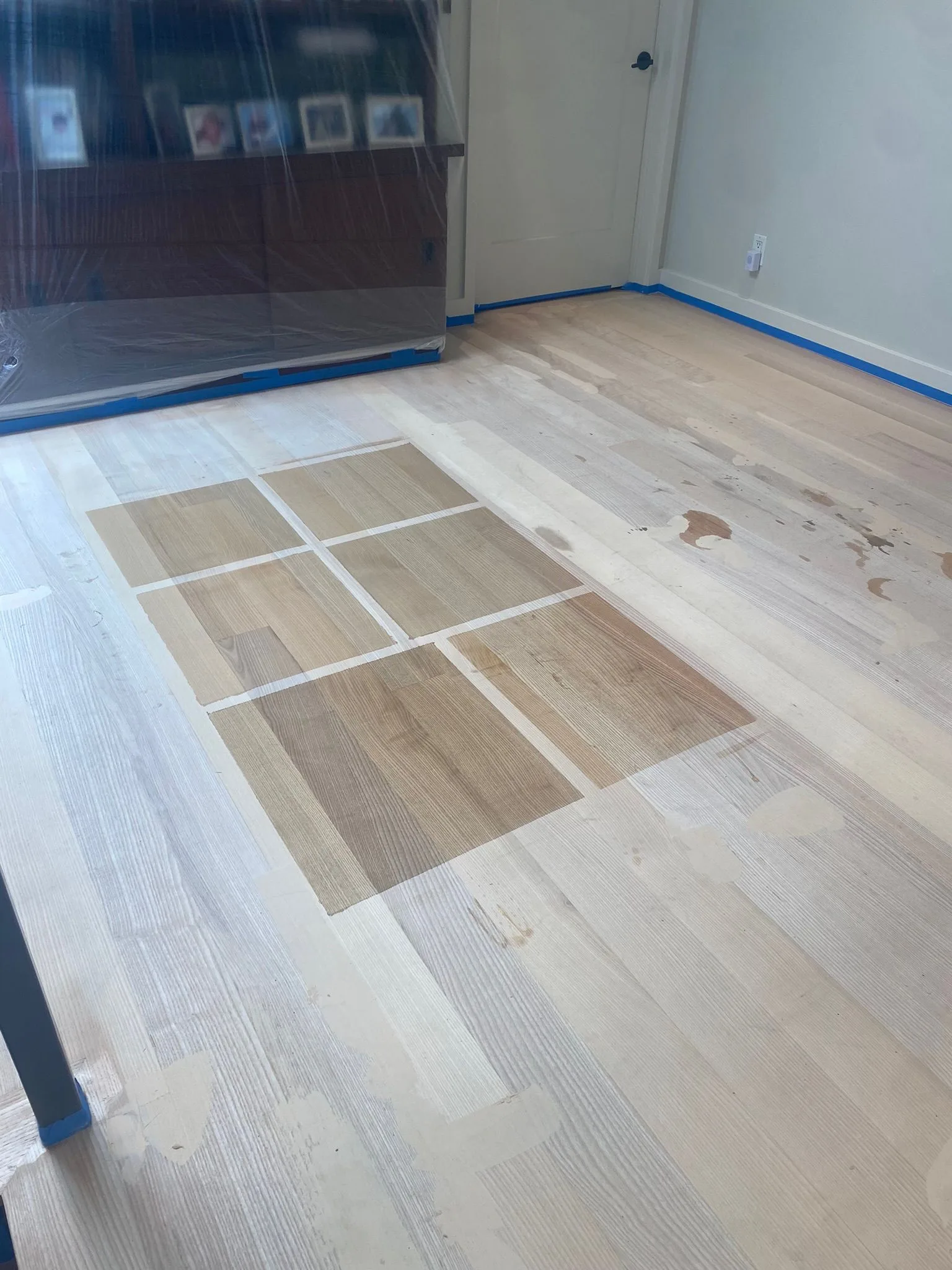Six stain samples taped out on a freshly sanded floor
