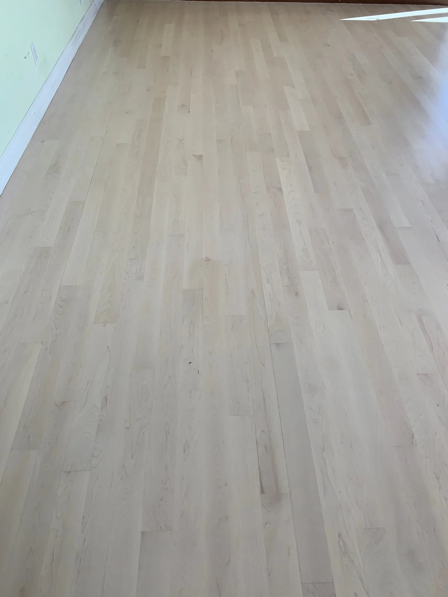 Light maple-toned strip flooring under a clear coat