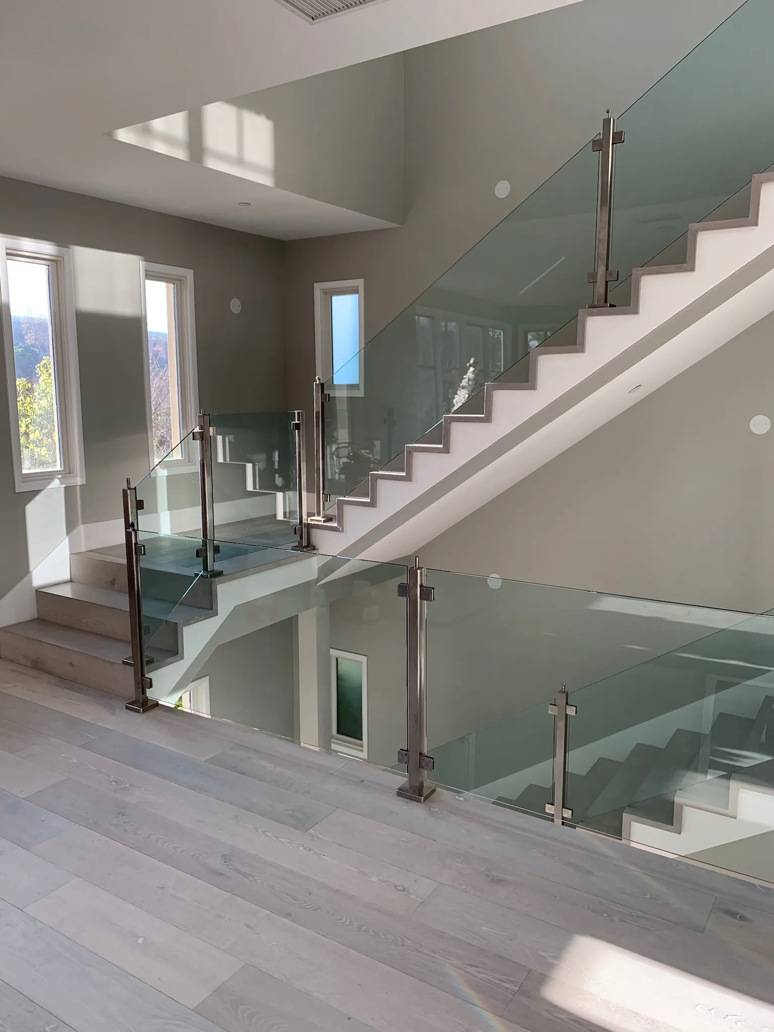 Glass-railed stair with light-stained wood treads and steel posts