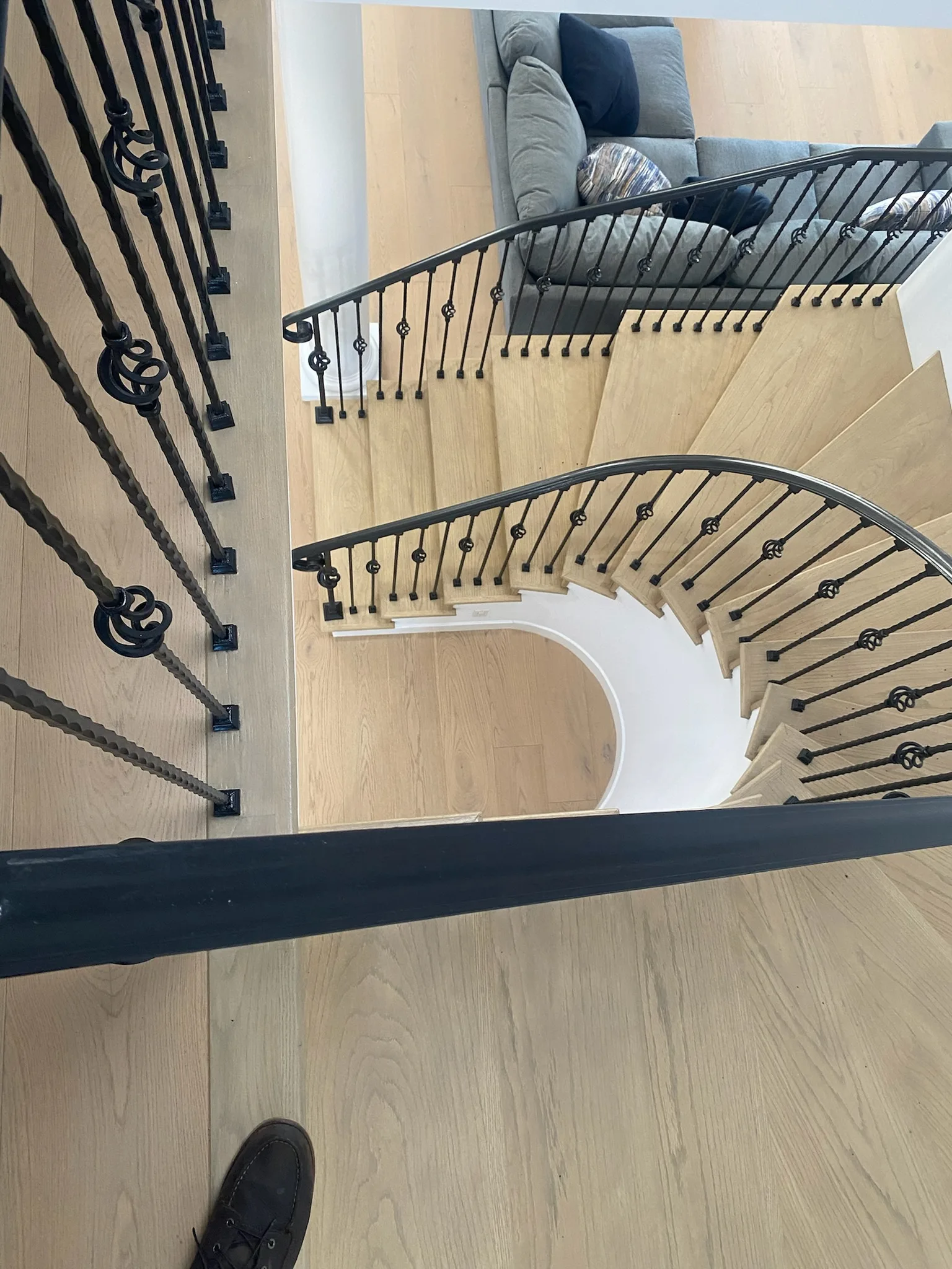 Oak treads sweeping under scrolled wrought-iron balusters