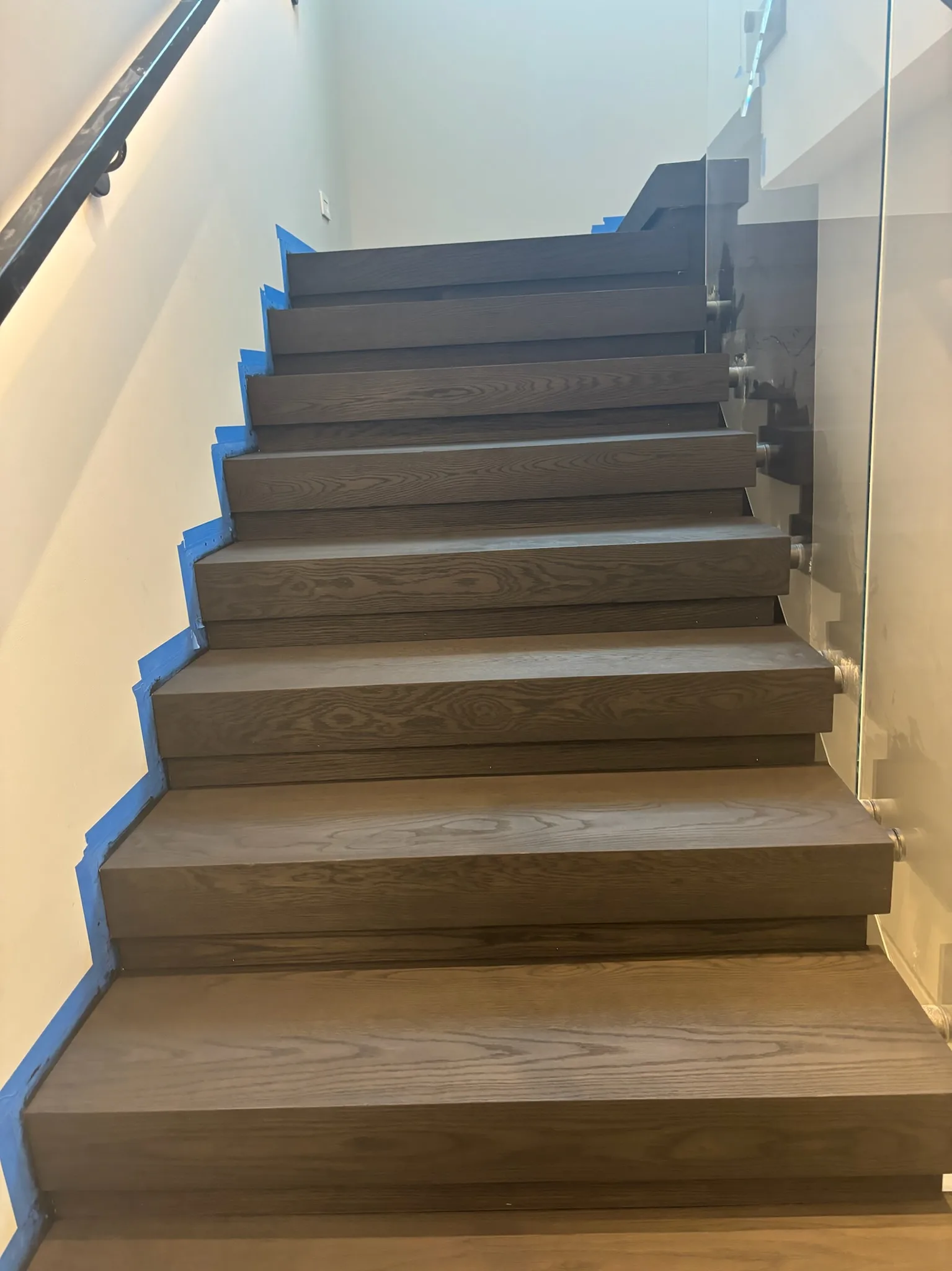 Freshly stained oak treads with walls masked in blue tape