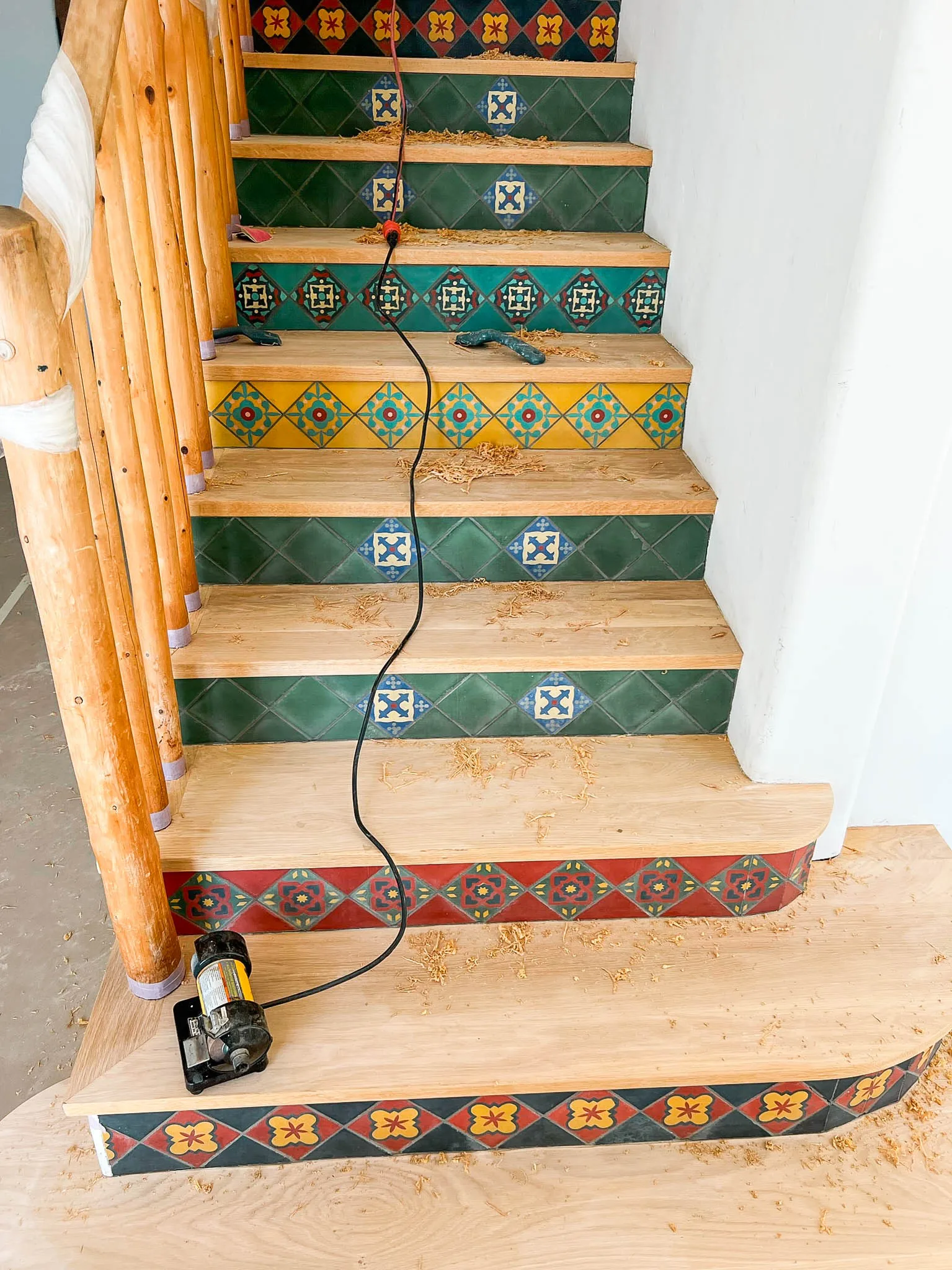 Raw oak treads being sanded above tile risers in Malibu