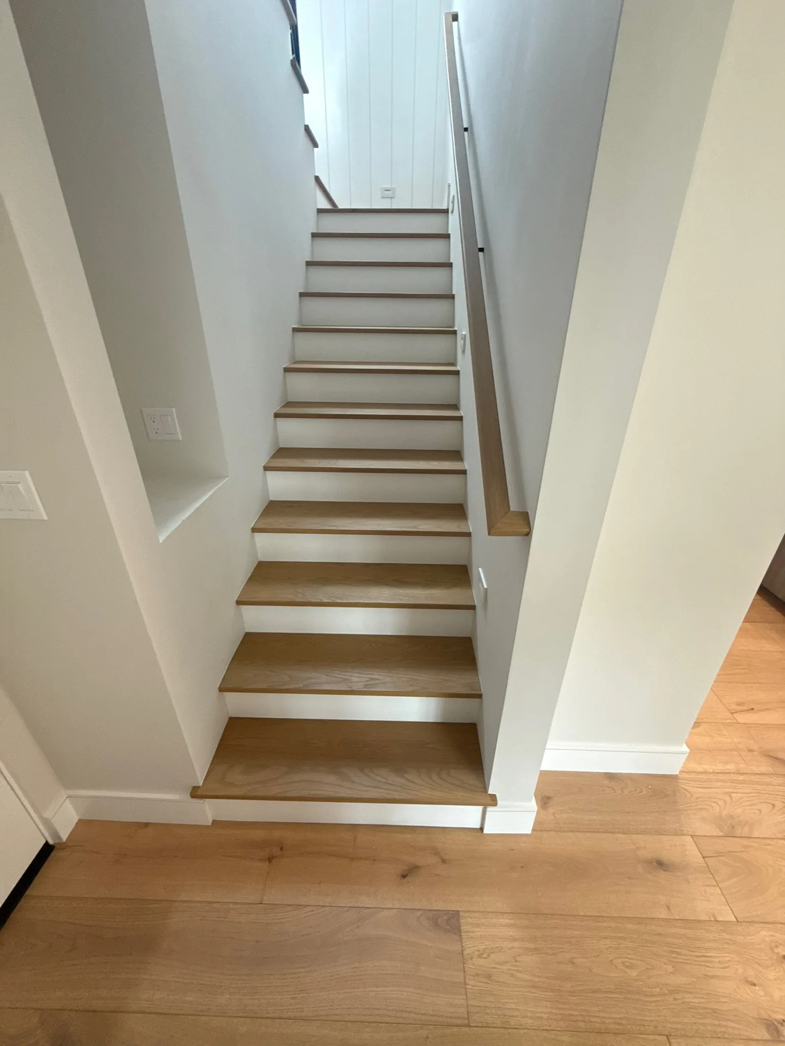 Oak treads and white risers with a wall-mounted oak handrail