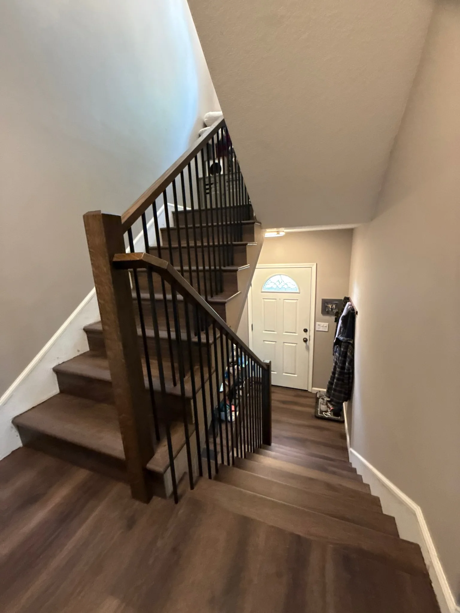 Dark plank treads and landing with black metal balusters and a wood newel