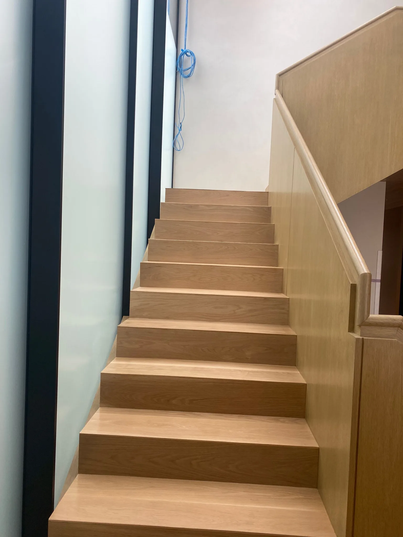 Waterfall oak stair beside an oak-panelled guard wall with handrail cap in Hermosa Beach