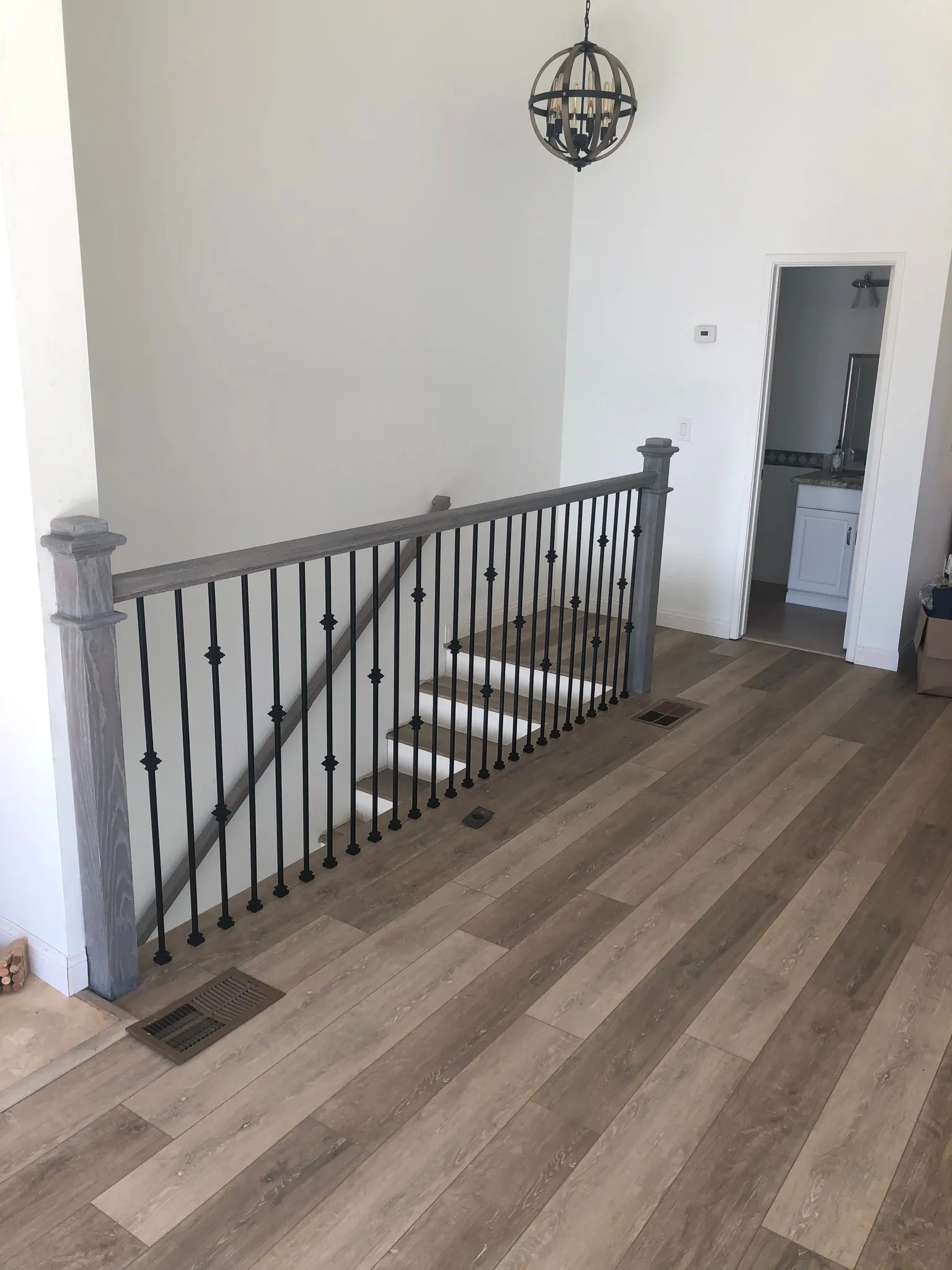 Wide grey oak-look vinyl plank across a landing with iron balusters