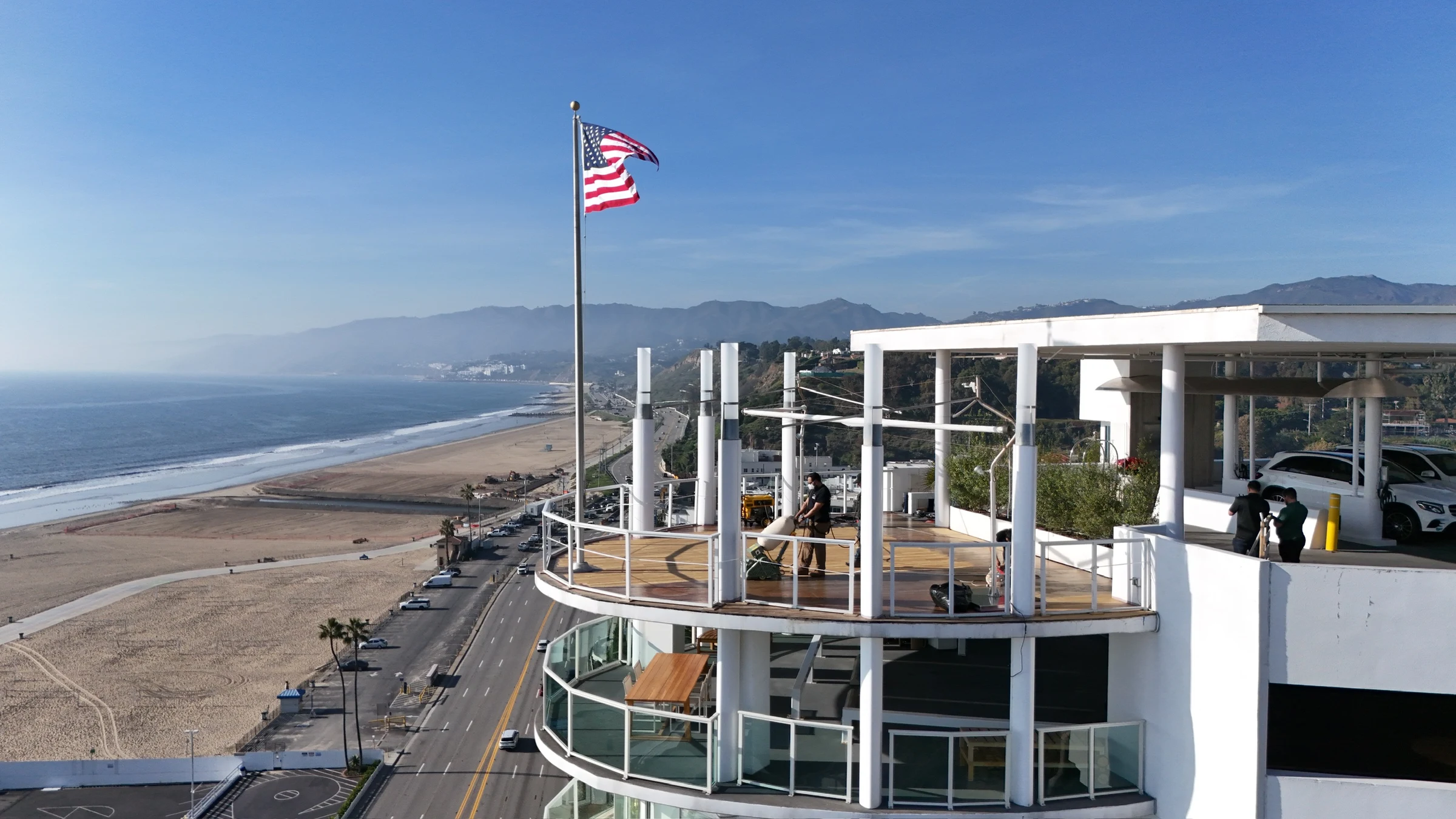Aerial view of the Cal Coast Flooring crew refinishing a curved oceanfront deck above the Pacific Coast Highway
