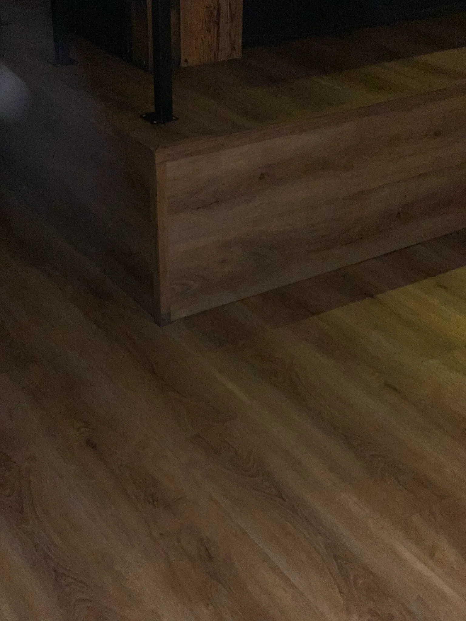Detail of the luxury vinyl plank flooring and matching clad platform Cal Coast Flooring installed at American Junkie