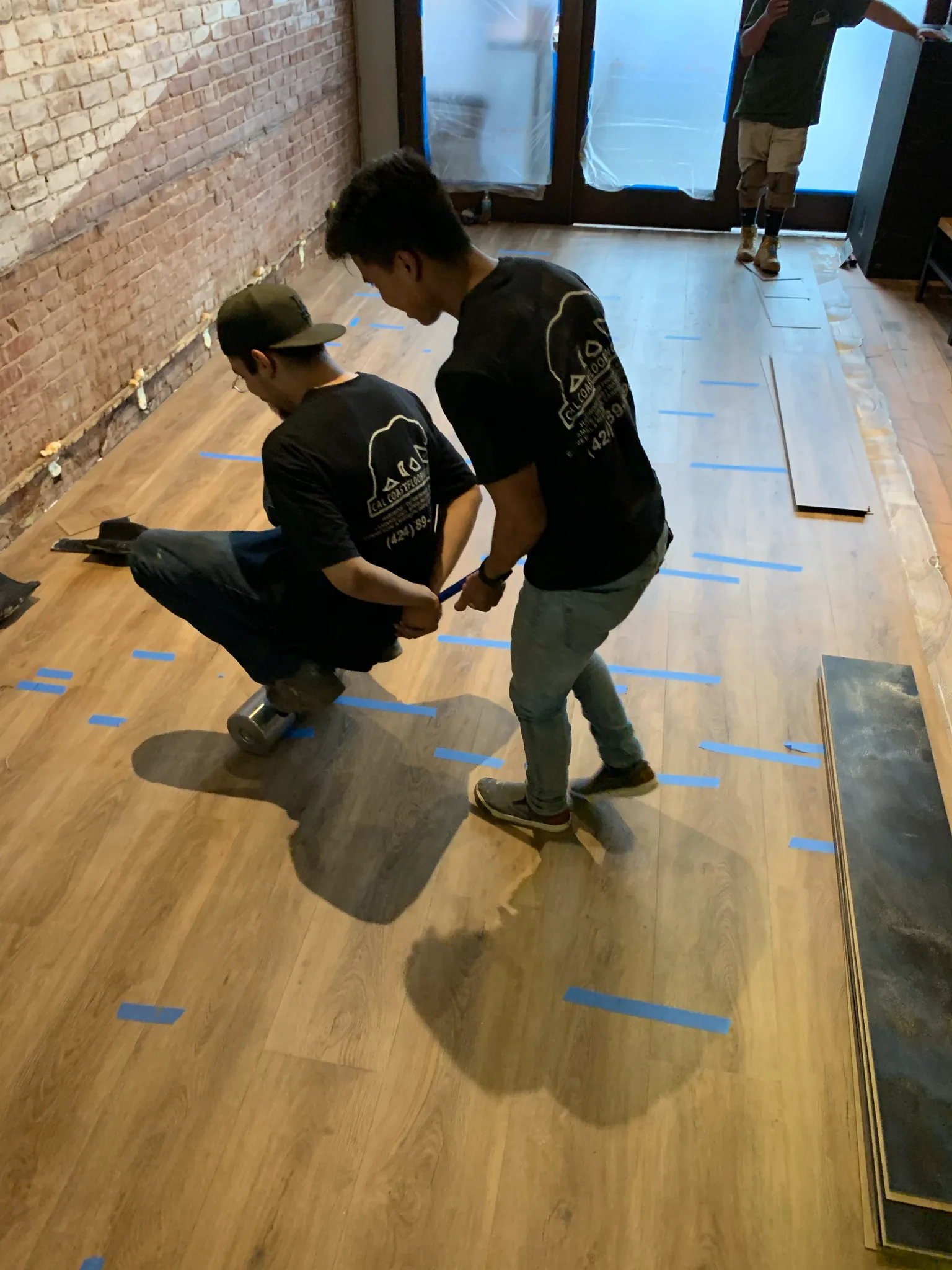 Work in progress: Cal Coast Flooring crew rolling the new glue-down luxury vinyl plank floor at American Junkie