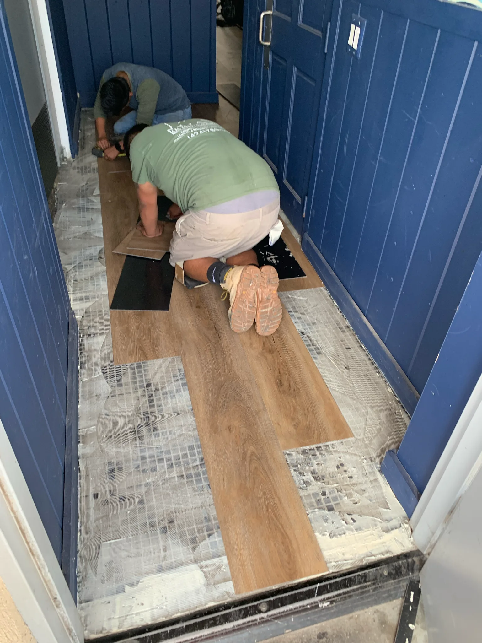 Work in progress: Cal Coast Flooring installers fitting LVP planks over adhesive in the American Junkie entry