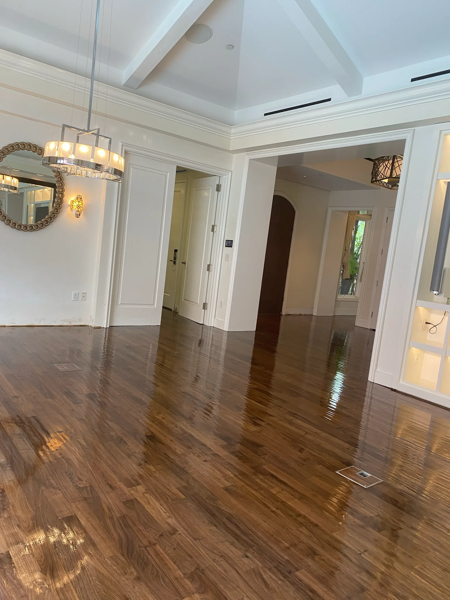Freshly finished walnut floor reflecting a chandelier in a white-paneled room at The Beverly Hills Hotel