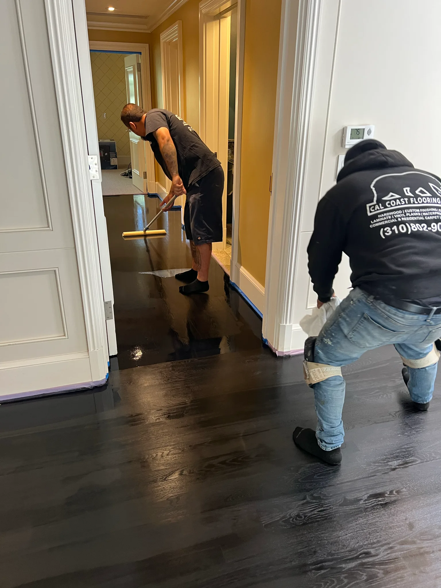 Work in progress: Cal Coast Flooring crew rolling dark finish onto a hardwood hallway at The Beverly Hills Hotel