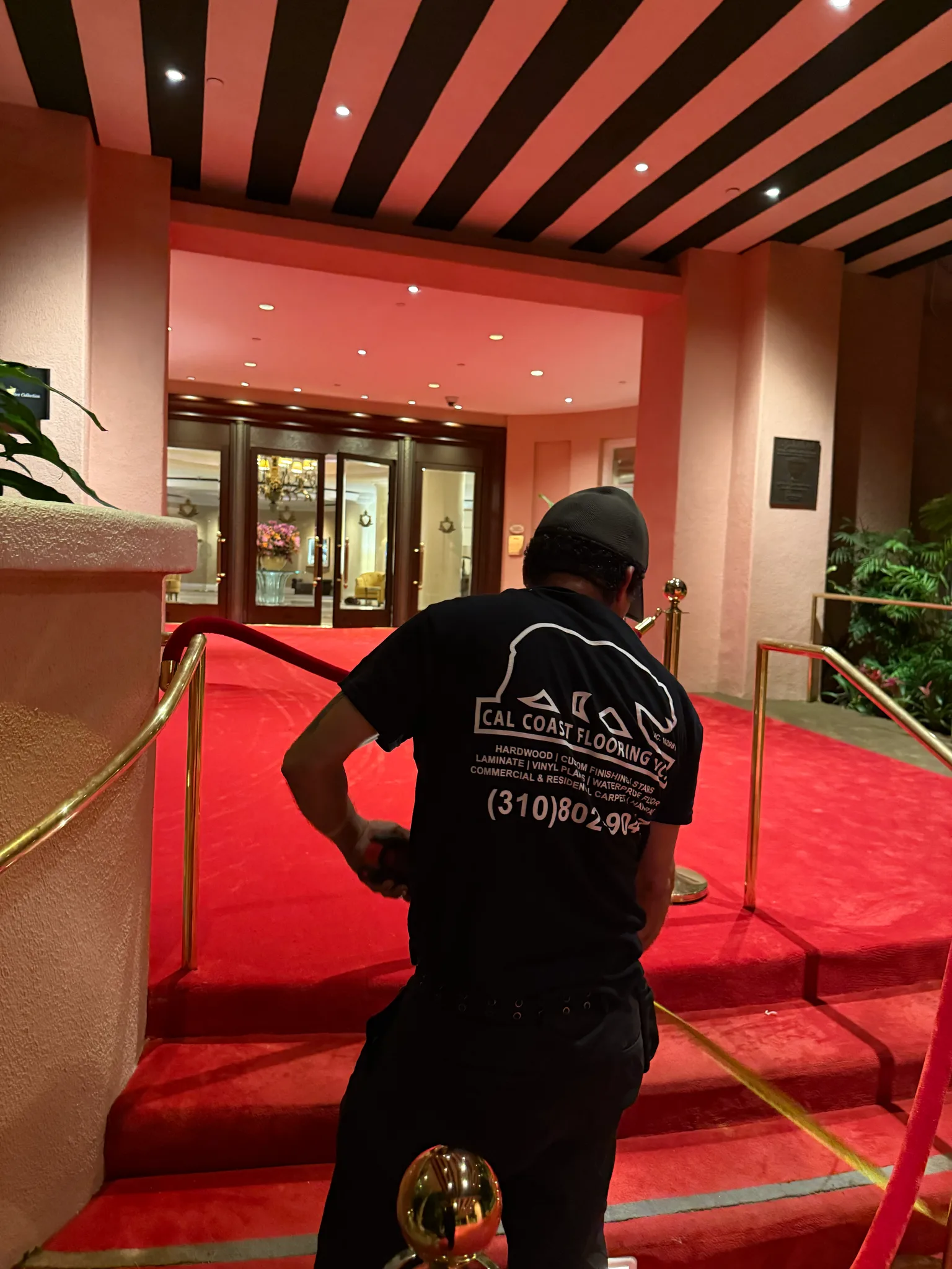 Work in progress: crew fitting red carpet on the entrance steps under the striped awning at The Beverly Hills Hotel